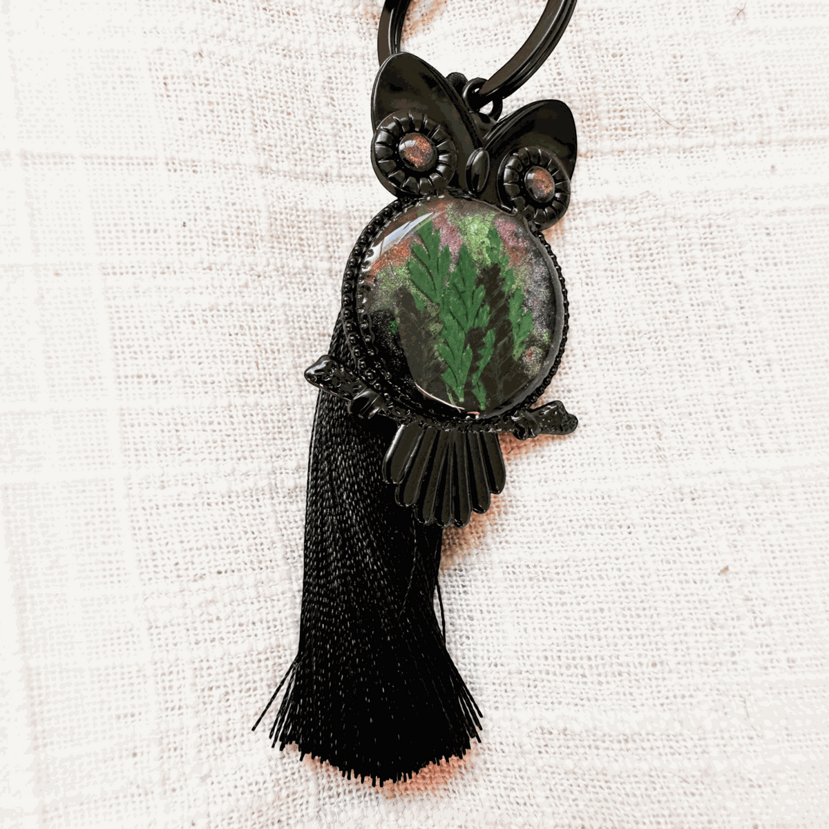 Bag Charm with a dark gunmetal owl, green pressed fern in shimmering resin, sparkling eyes and long black tassel