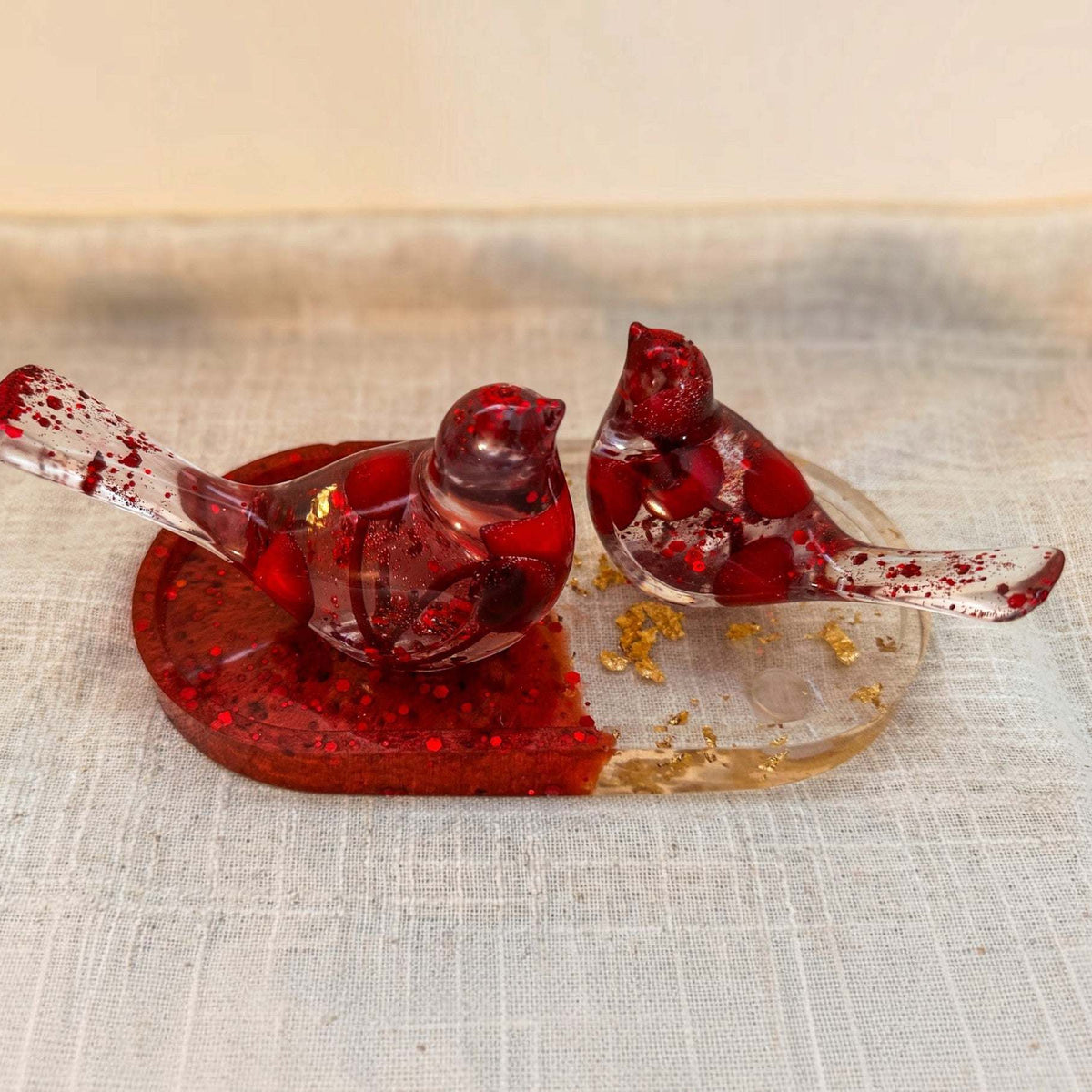 Berry resin bird set seen from above on its red and gold oval tray
