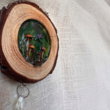 boreal forest suncatcher in a bark-edged wood slice, featuring tiny mushrooms and moss beneath an iridescent dragonfly
