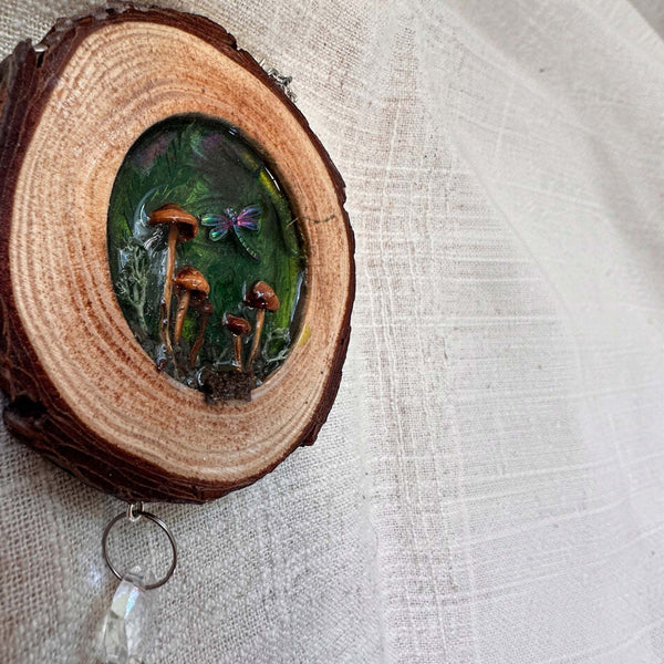 boreal forest suncatcher in a bark-edged wood slice, featuring tiny mushrooms and moss beneath an iridescent dragonfly
