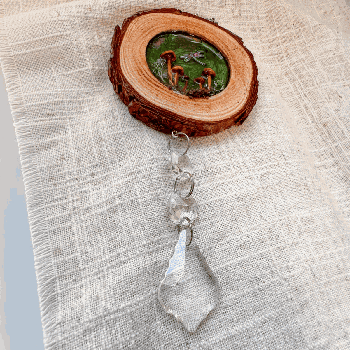 boreal forest suncatcher with a natural bark-edged wood slice, tiny mushrooms and moss, and a clear hanging crystal