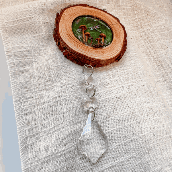 boreal forest suncatcher with a natural bark-edged wood slice, tiny mushrooms and moss, and a clear hanging crystal