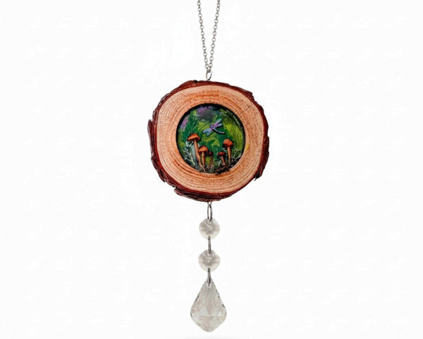 boreal forest suncatcher with a bark-edged wood slice, colorful mushroom scene, purple dragonfly and hanging clear crystals