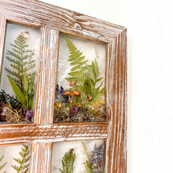 boreal forest window art in a distressed whitewashed wood frame with green ferns, mushrooms, moss and dried flowers in resin panes