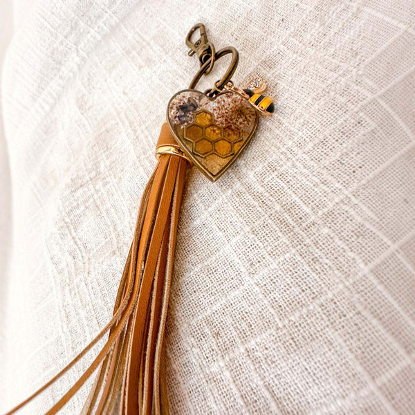 bumble bee resin keychain with an amber heart pendant, honeycomb pattern, pressed flowers, bee charm and tan tassel