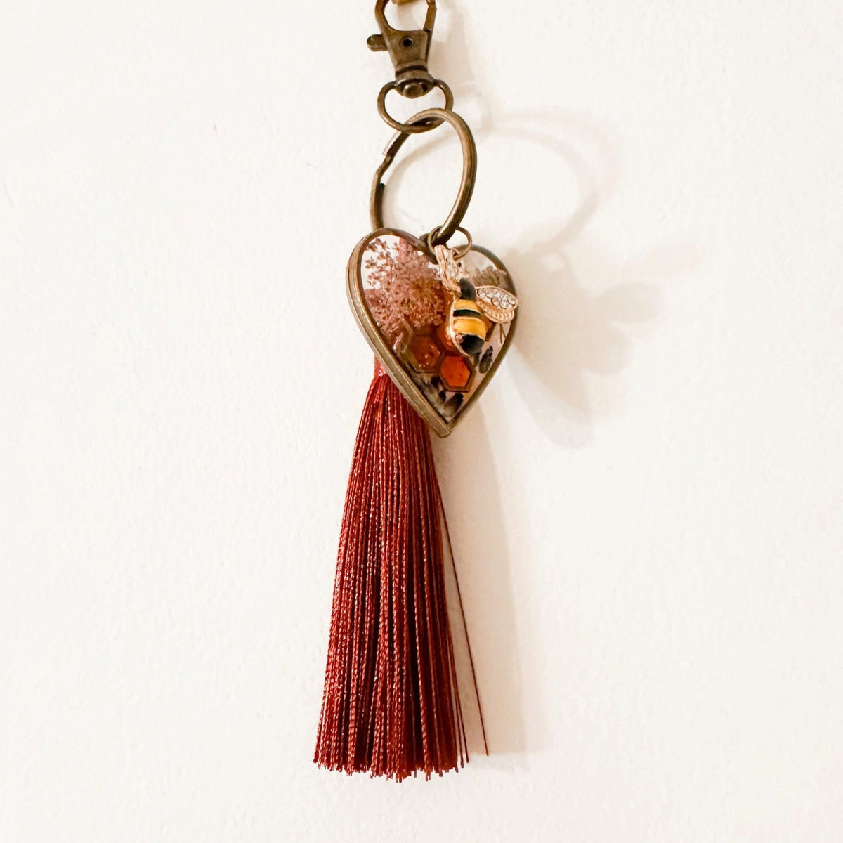 bumble bee resin keychain with a bronze heart frame, amber resin, tiny bee detail and rust red tassel