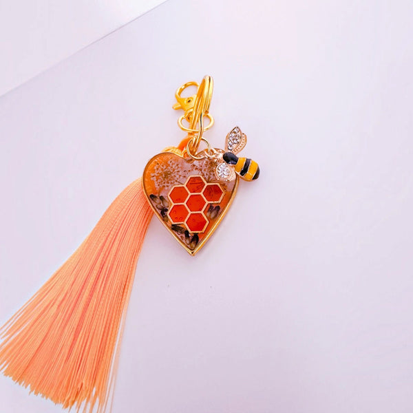 bumble bee resin keychain with a honey-gold heart, red honeycomb detail, floral inclusions, bee charm and coral tassel