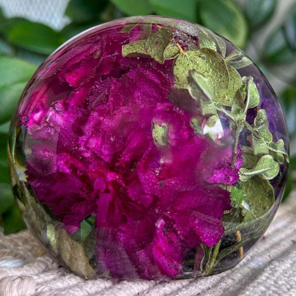 Handcrafted floral resin sphere with real dark pink and purple carnations and LED light base glowing indoors