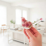 Dried flower resin bird with clear resin, pink clover blossoms, fine stems, and a rosy floral tail 
