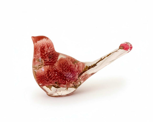 Dried flower resin bird in clear resin, featuring rosy pink clover blossoms and delicate stems extending into the tail.