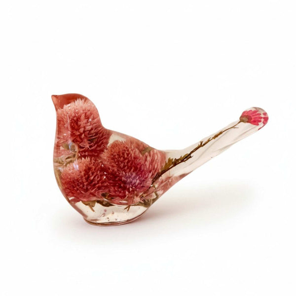 Dried flower resin bird in clear resin, featuring rosy pink clover blossoms and delicate stems extending into the tail.