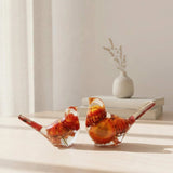 Resin Bird Pair with clear resin bodies, vivid orange and red dried flowers, and slender red botanical tails.