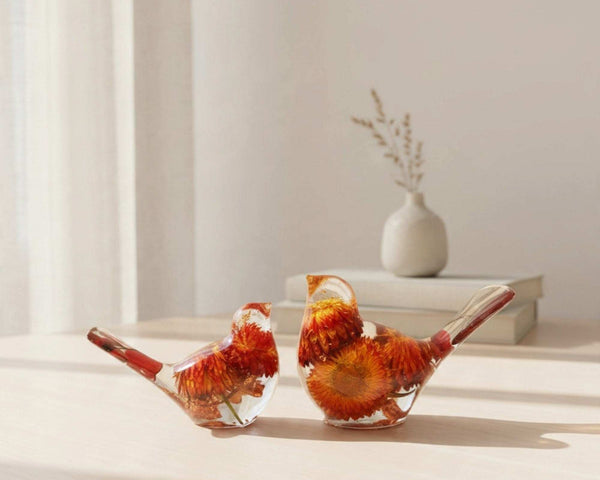 Resin Bird Pair with clear resin bodies, vivid orange and red dried flowers, and slender red botanical tails.