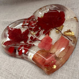 Red maple leaf resin tray in clear glossy heart-shaped resin, with crimson and blush foliage and scattered gold leaf flakes.