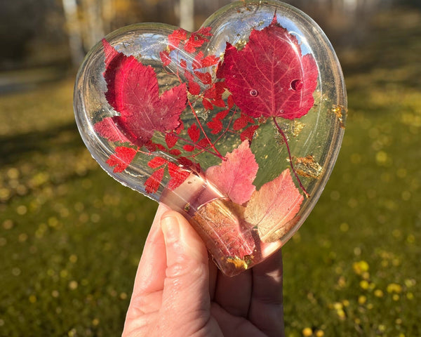Red maple leaf resin tray in a glossy clear heart shape, with crimson and blush foliage and scattered gold flakes.