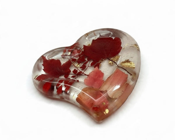 Heart-shaped red maple leaf resin tray with clear glossy resin, preserved crimson and blush foliage, and scattered gold leaf.
