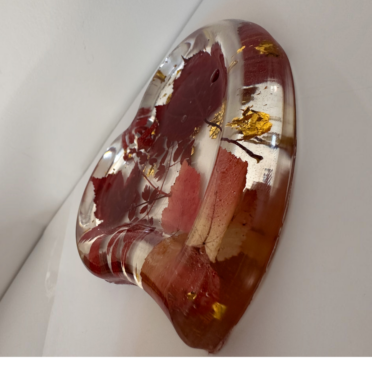 Red maple leaf resin tray in a heart shape, with crimson and blush foliage, clear glossy resin and scattered gold leaf.