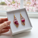 Handcrafted geometric gold-framed pink butterfly resin earrings with pink flowers and a butterfly.