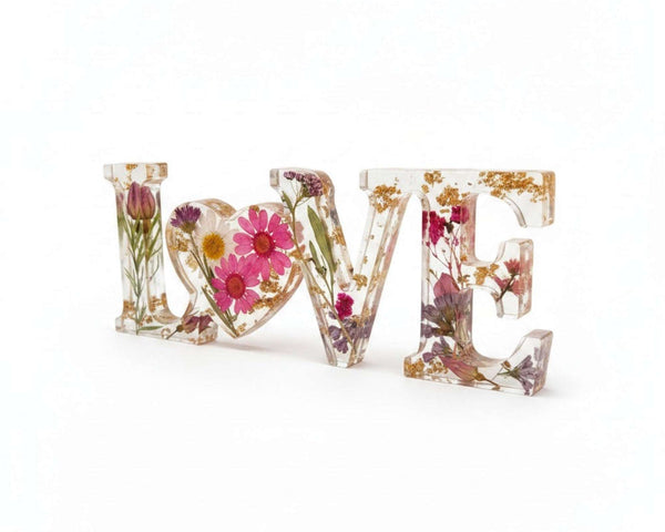 Wildflower resin word art spelling LOVE with pink daisies, white daisy, purple wildflowers, rose buds, greenery, and gold leaf flakes
