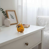 A teardrop-shaped resin ring holder containing a real Black-Eyed Susan and sunflower with gold leaf accents on a wooden surface.