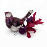 Fuchsia resin bird decor in clear glossy resin with purple and crimson preserved blooms, featuring a translucent head and tail.