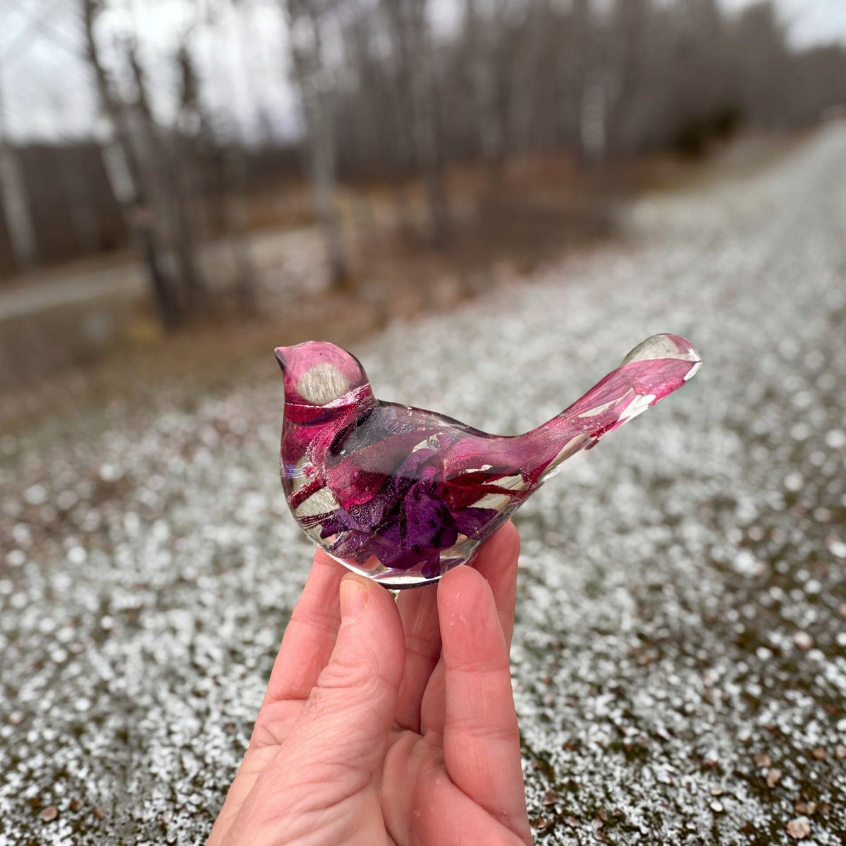 Fuchsia resin bird decor with clear glossy resin, embedded purple and pink petals, and a long curved tail.