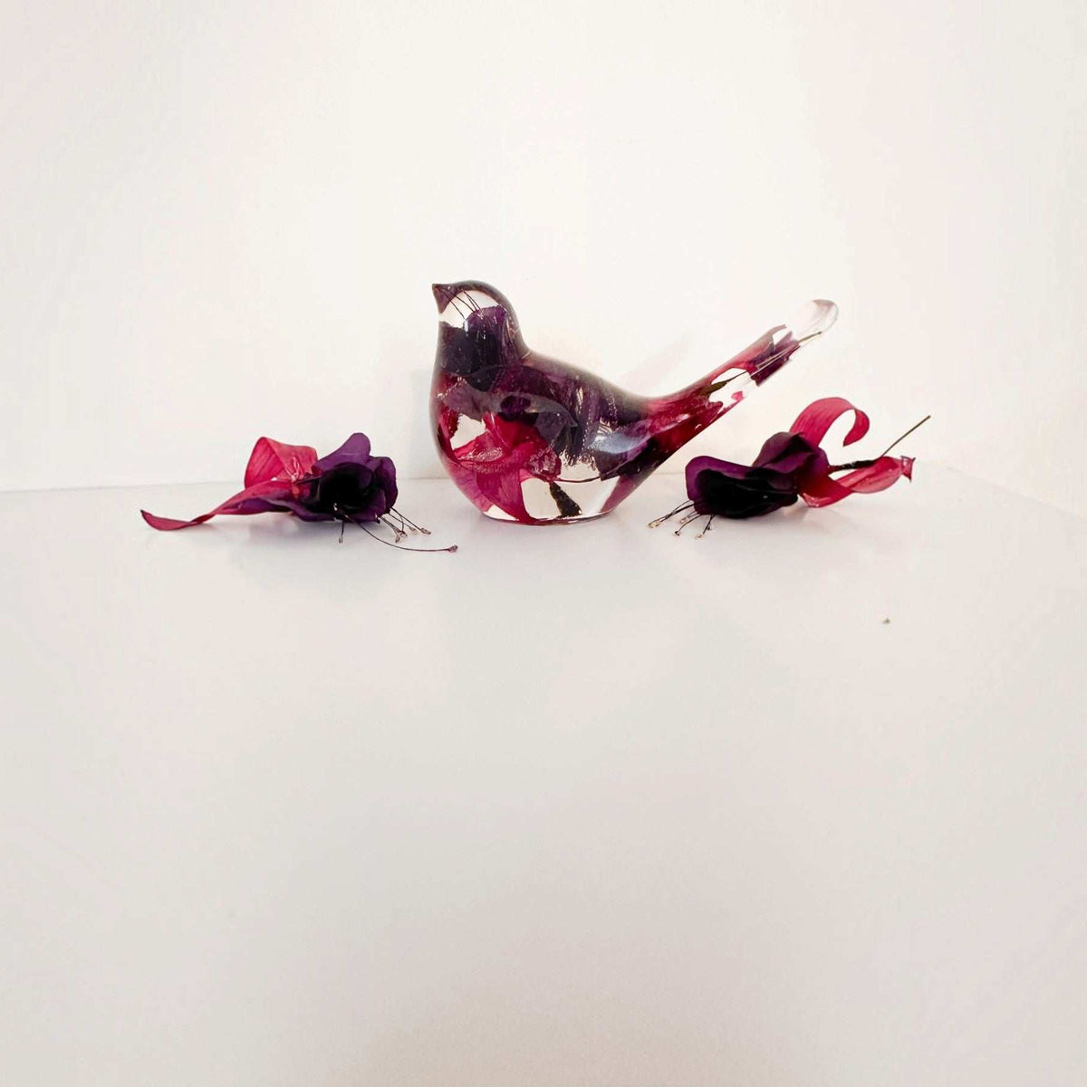 Fuchsia resin bird decor with clear glossy resin, deep purple and crimson pink petals, and a translucent tail.