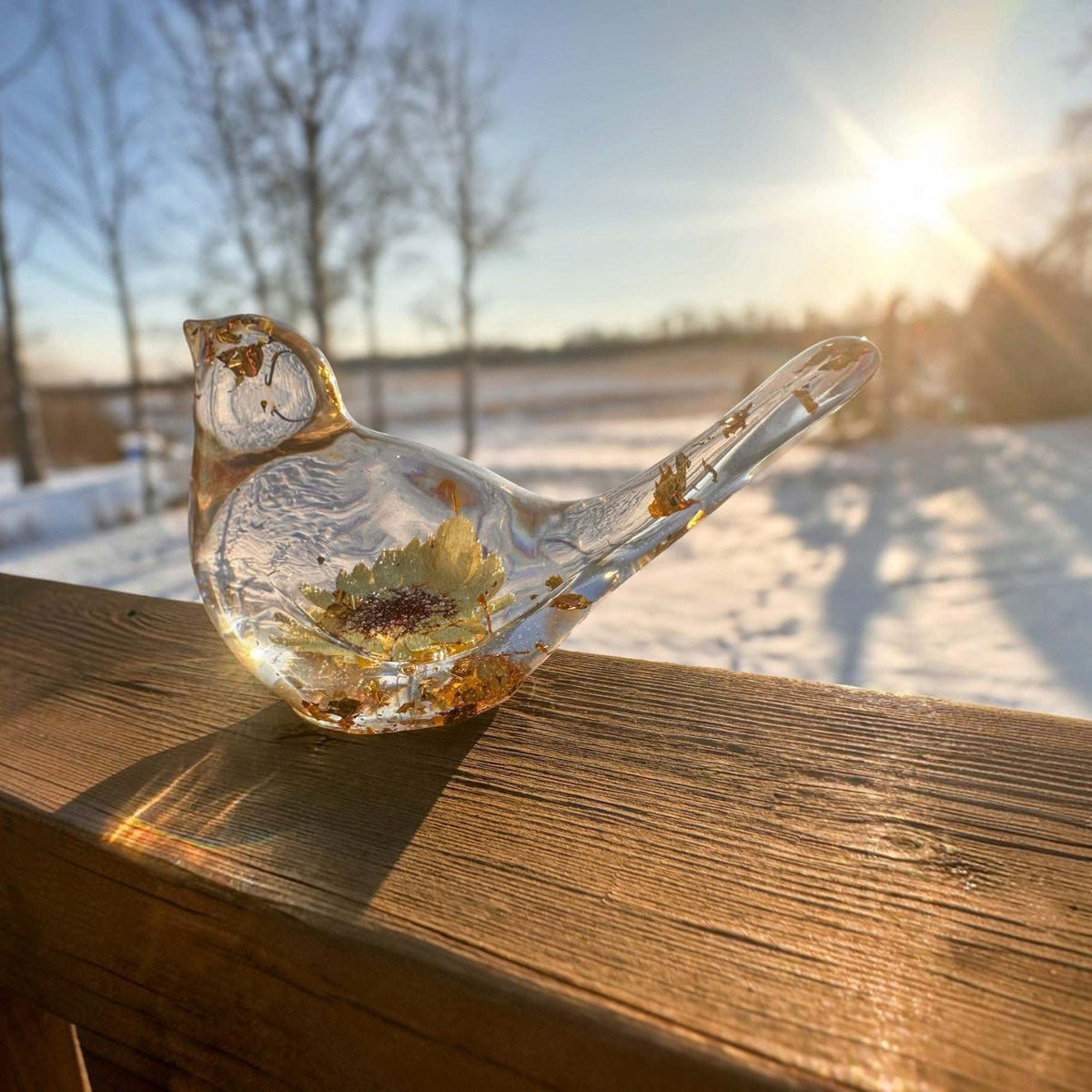 Gold leaf resin bird on a windowsill with winter sun coming through the resin