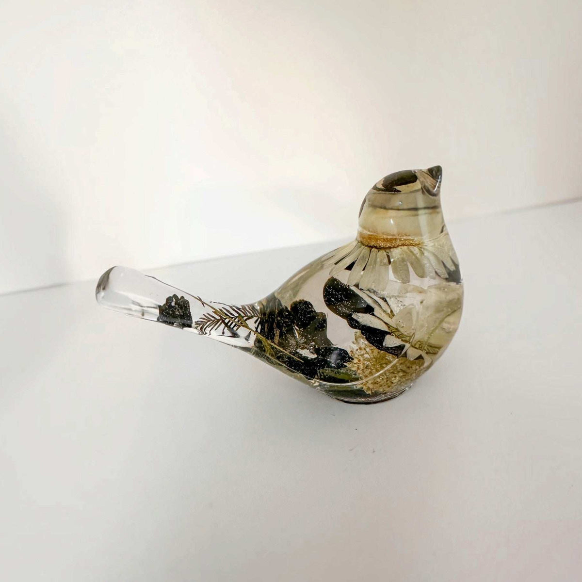 Close up of a handmade chickadee showing black and white dried blooms in resin