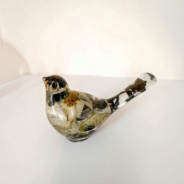 Front view of a handmade chickadee resin bird with black cap and white body flowers