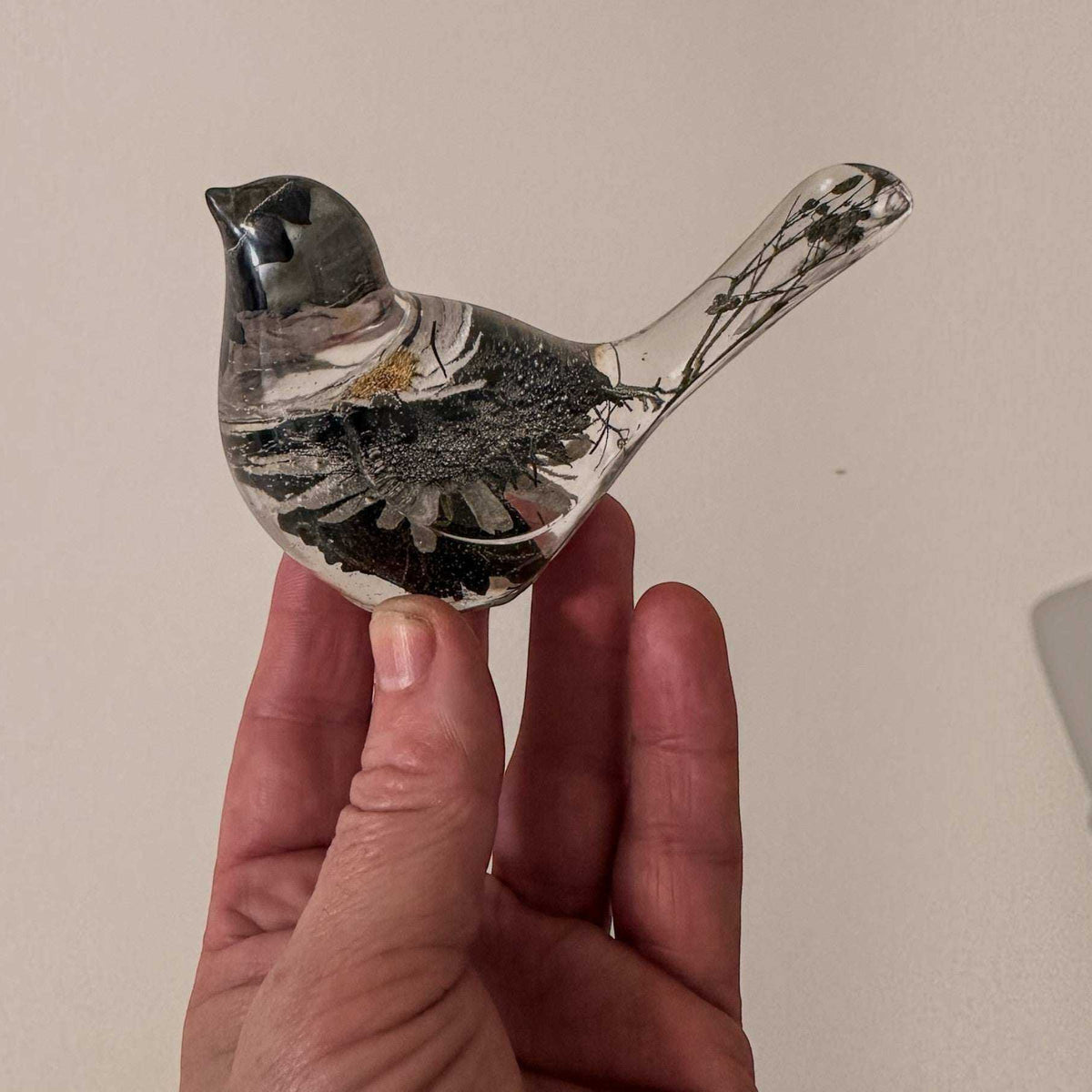 Side view of a handmade chickadee resin bird with white flowers along the wing