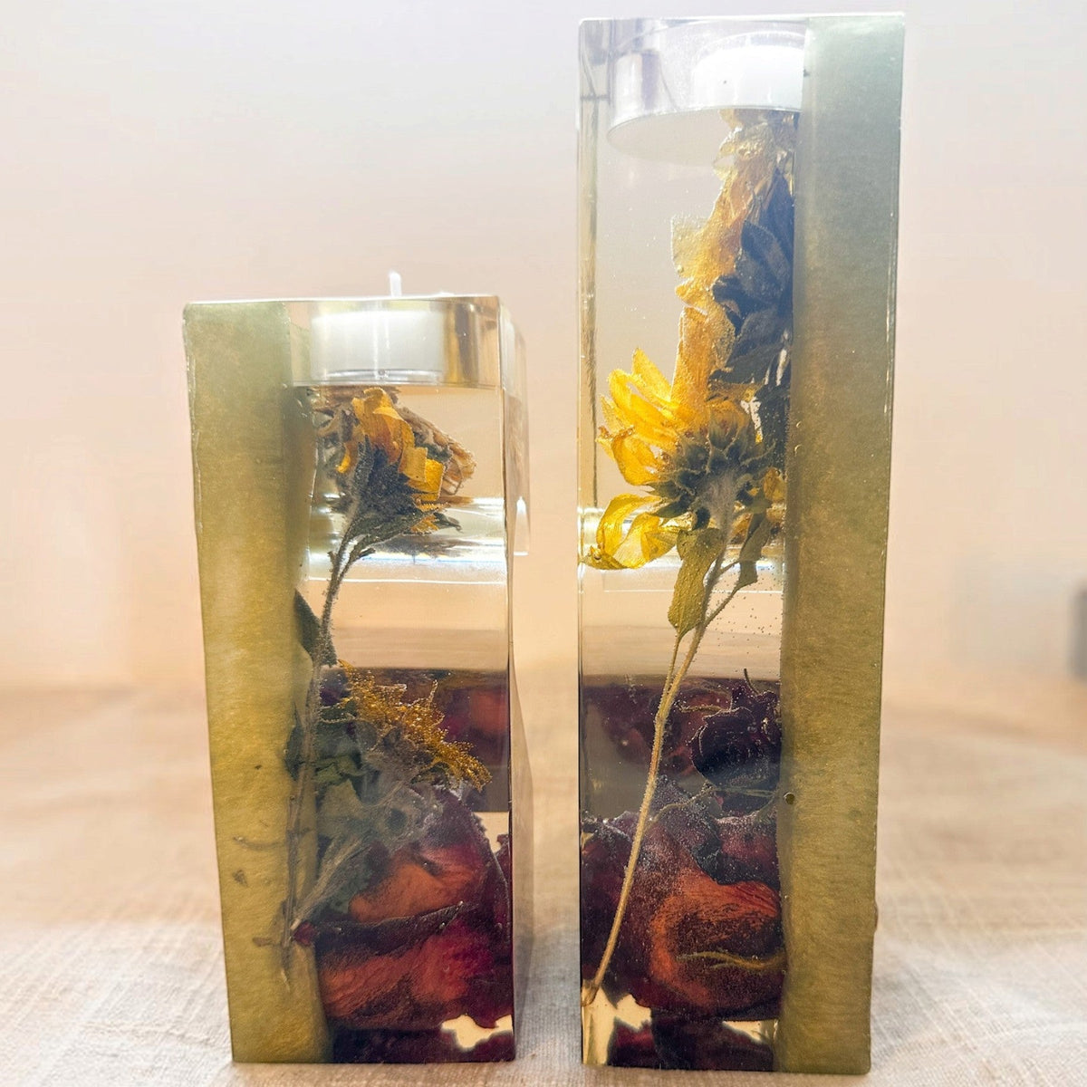 heart tealight holder set in clear resin with sage green sides, dried yellow sunflowers and deep red roses