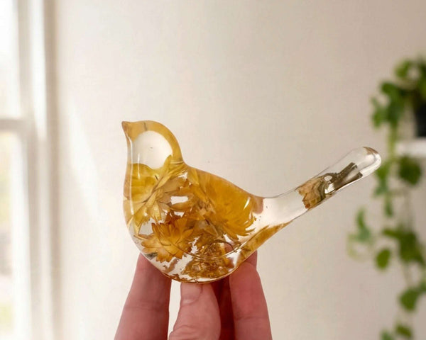 Yellow Strawflower Resin Bird with clear resin, honey-gold dried flowers, and a transparent tail holding a small bud.
