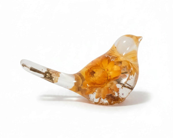 Yellow Strawflower Resin Bird figurine in clear resin with amber-orange dried flowers, a clear head and slender tail with a stem inside.