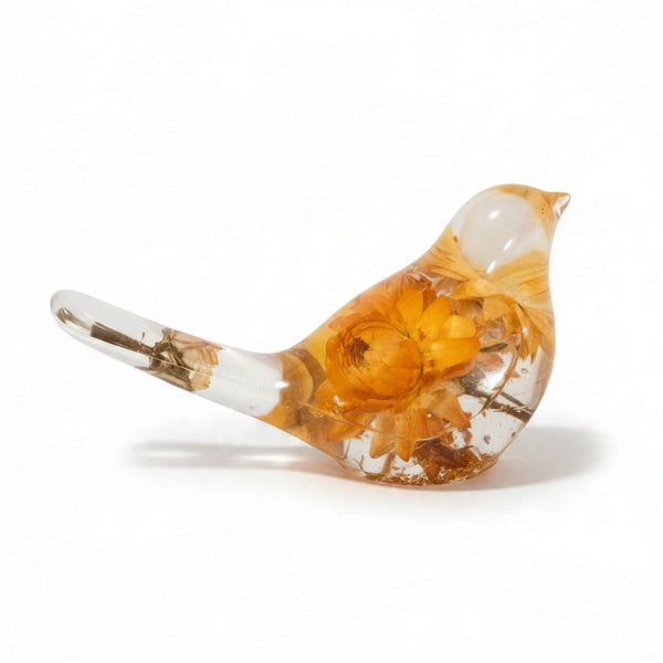 Yellow Strawflower Resin Bird figurine in clear resin with amber-orange dried flowers, a clear head and slender tail with a stem inside.