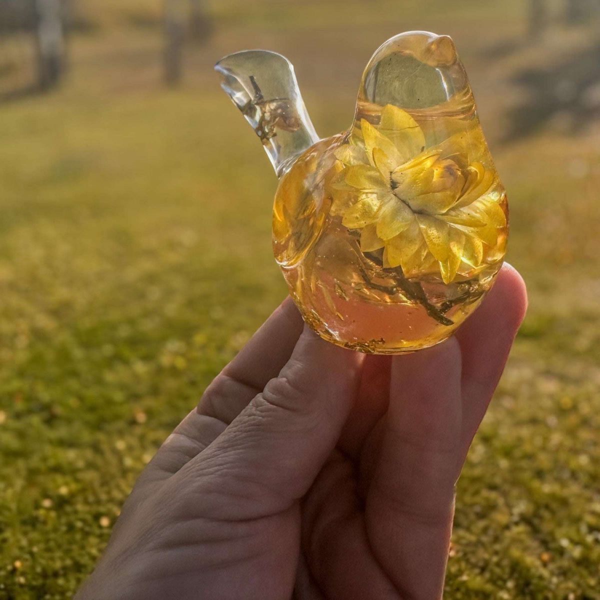 Yellow Strawflower Resin Bird figurine in clear amber resin with layered golden dried flowers and a transparent tail.