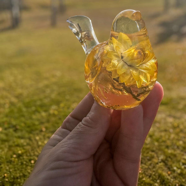 Yellow Strawflower Resin Bird figurine in clear amber resin with layered golden dried flowers and a transparent tail.