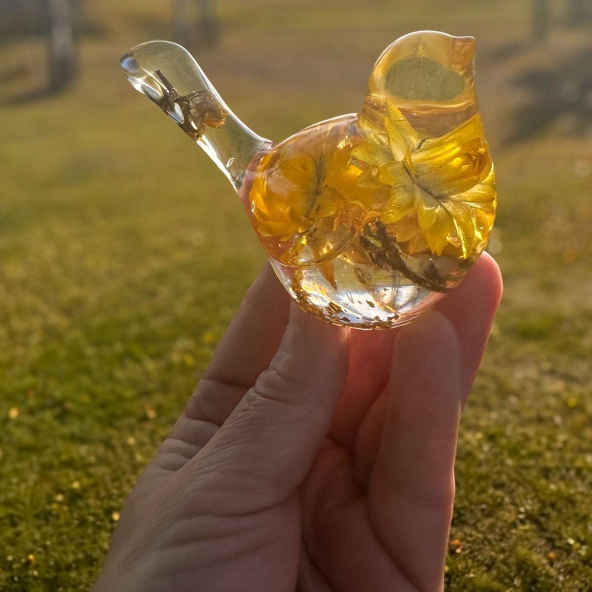 Yellow Strawflower Resin Bird figurine in clear resin with golden yellow dried flowers, translucent head and tail, and gold flecks at the base.