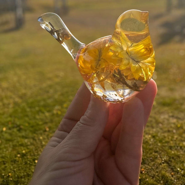Yellow Strawflower Resin Bird figurine in clear resin with golden yellow dried flowers, translucent head and tail, and gold flecks at the base.