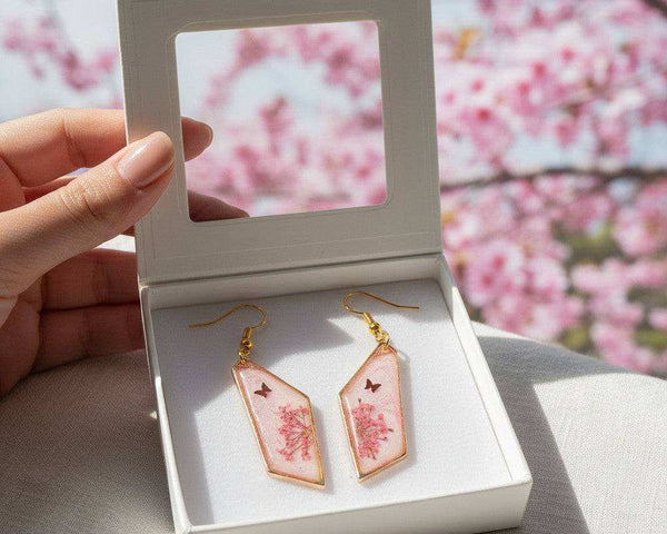 Handcrafted geometric gold-framed pink butterfly resin earrings with pink flowers and a butterfly.