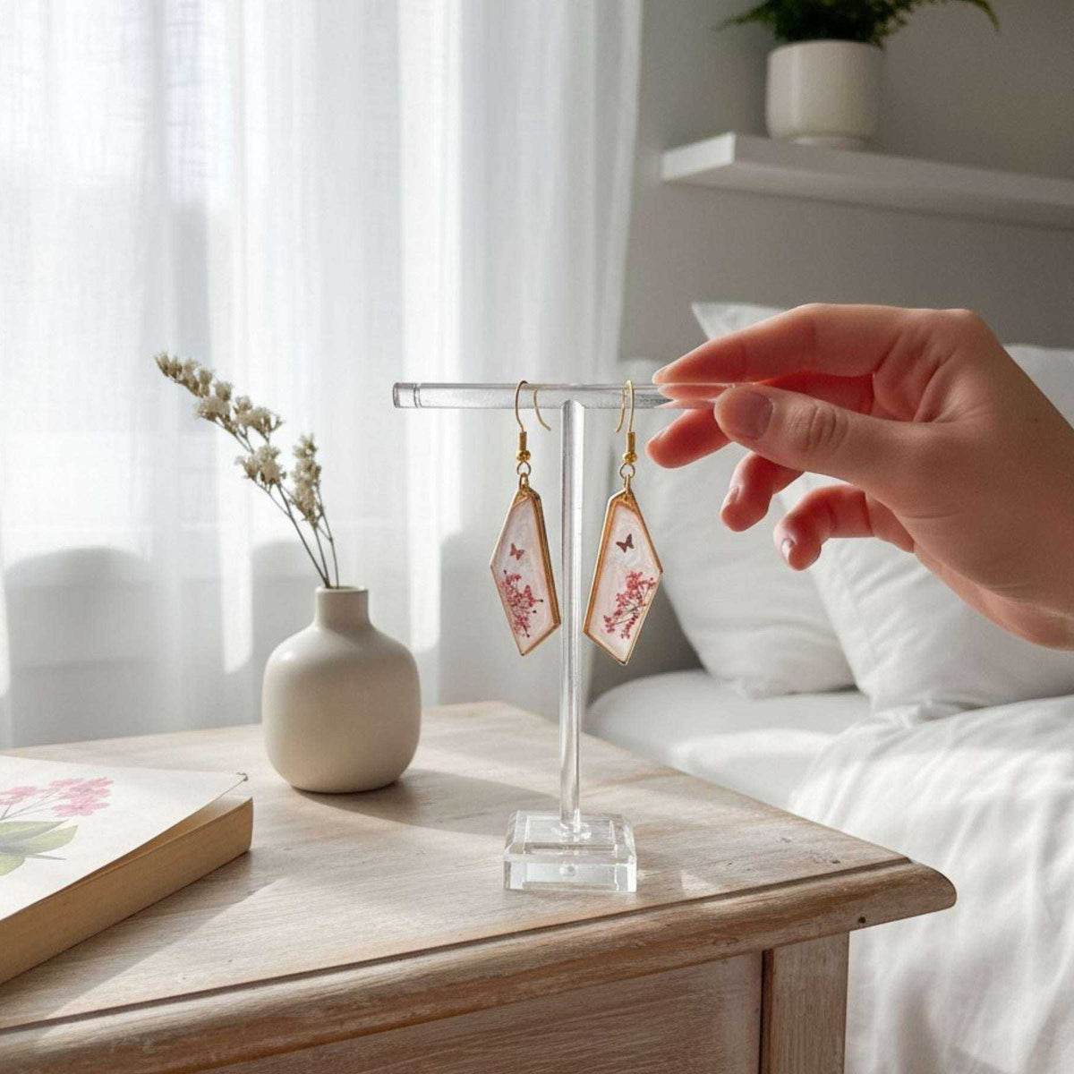 Handcrafted geometric gold-framed pink butterfly resin earrings with pink flowers and a butterfly.