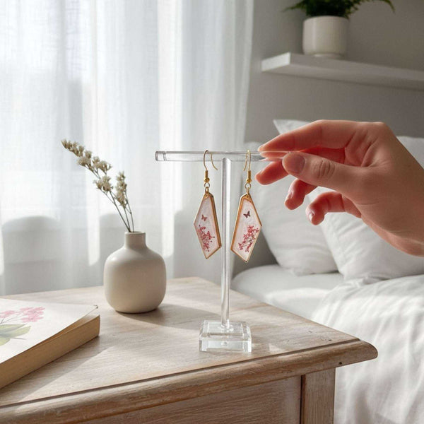 Handcrafted geometric gold-framed pink butterfly resin earrings with pink flowers and a butterfly.