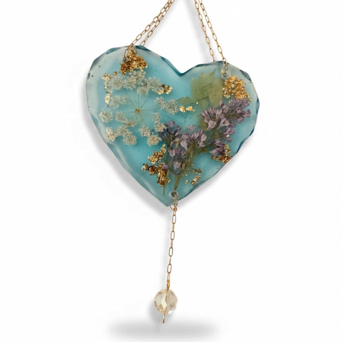 Glow in the dark heart suncatcher with blue resin, real pressed lilac and white wildflowers, gold leaf accents, and hanging crystal drop.