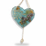 Glow in the dark heart suncatcher with blue resin, real pressed lilac and white wildflowers, gold leaf accents, and hanging crystal drop.