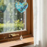 Glow in the dark heart suncatcher made of blue resin with real pressed wildflowers, gold leaf accents, and hanging crystal prisms.