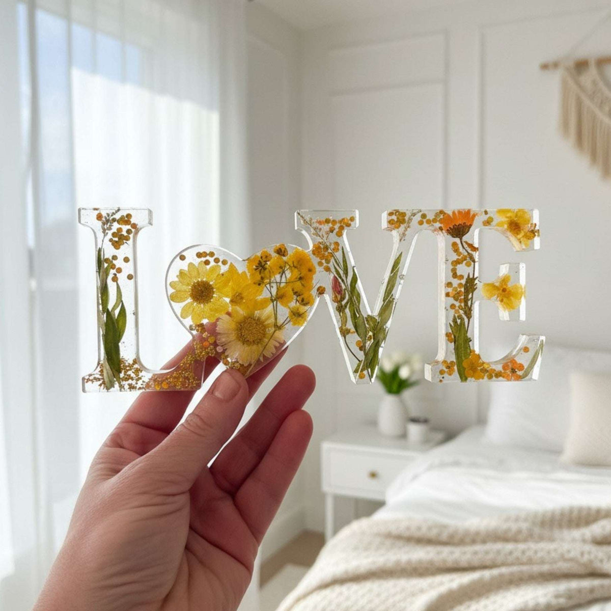 Pressed flower resin love sign spelling LOVE in clear resin with yellow wildflowers and a heart-shaped O centerpiece
