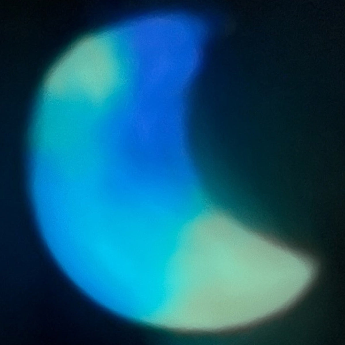 Luna Glow crescent moon keychain glowing vivid blue with green luminous patches and a softly curved resin shape