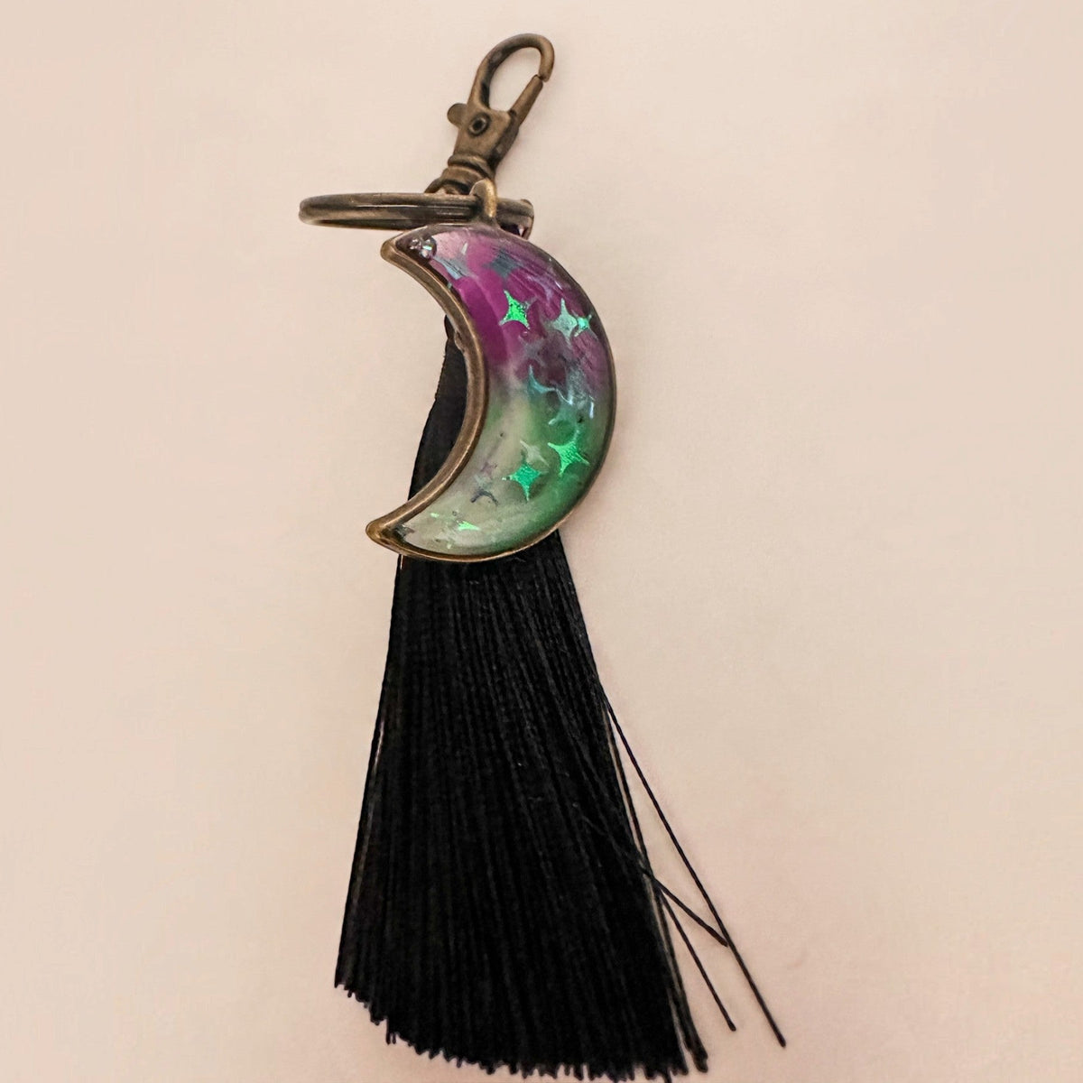 Luna Glow crescent moon keychain in purple and green marbled resin with glowing stars, antique bronze hardware and black tassel