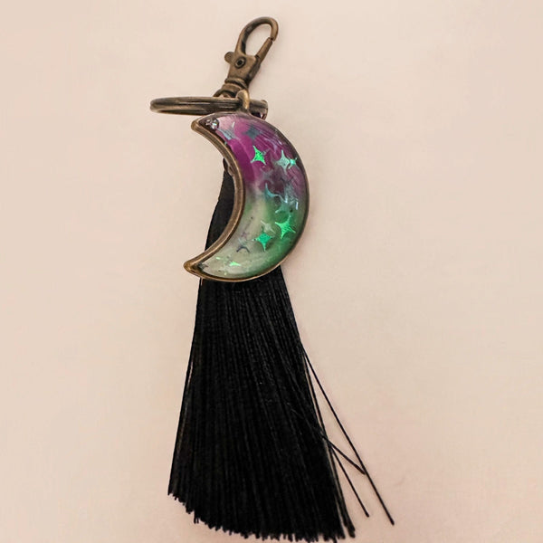 Luna Glow crescent moon keychain in purple and green marbled resin with glowing stars, antique bronze hardware and black tassel