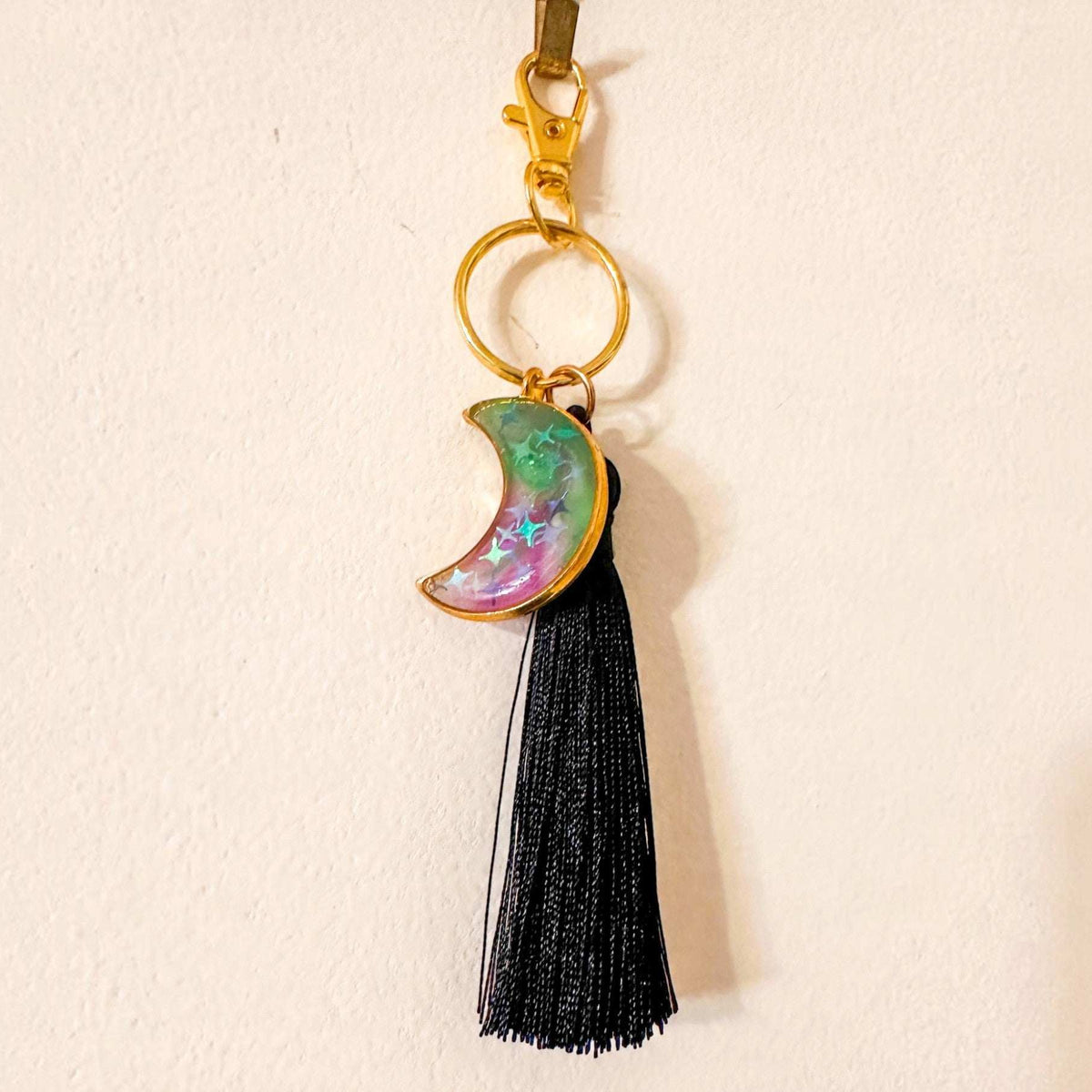 Luna Glow crescent moon keychain in shimmering pink, green and purple resin with gold-tone frame and black tassel